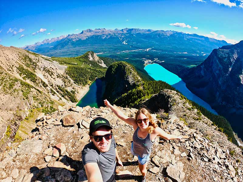 Young man and woman standing at a summit of a mountain