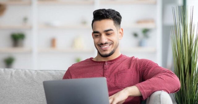 Handsome arab guy surfing on Internet, using laptop