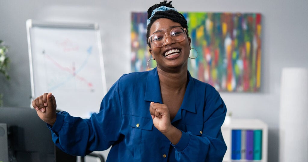 Smiling young woman dancing at the office