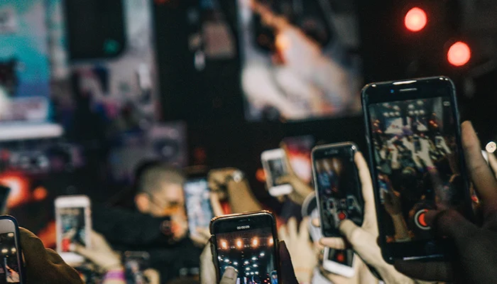 Phones held up at an event, recording