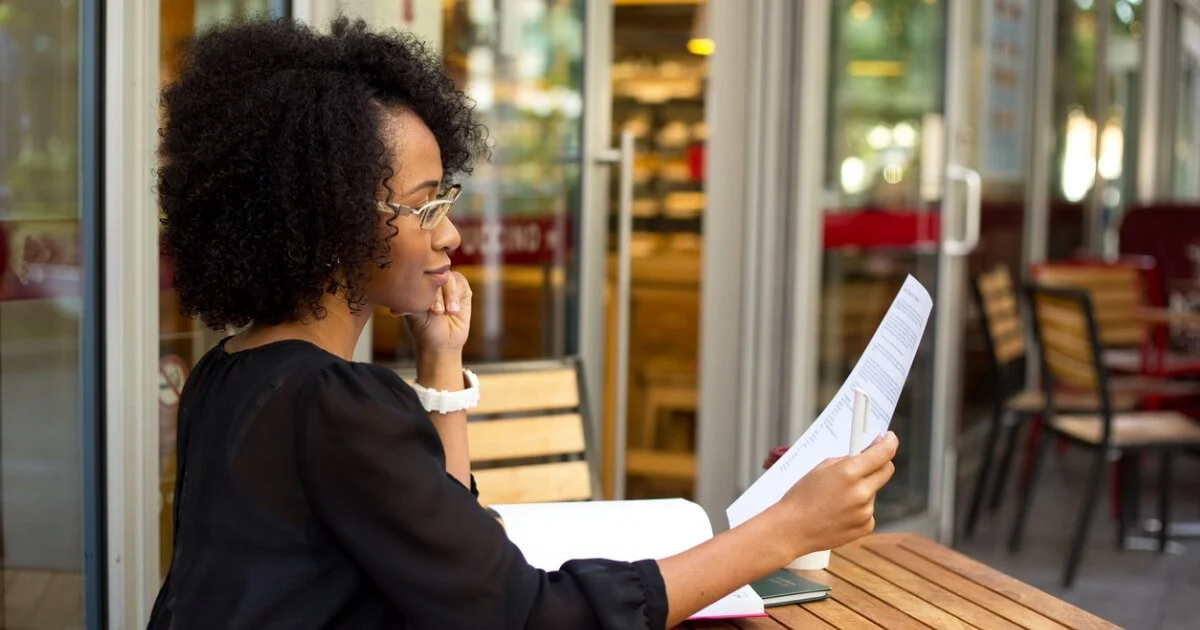 Woman sitting at table holding a piece of paper to read