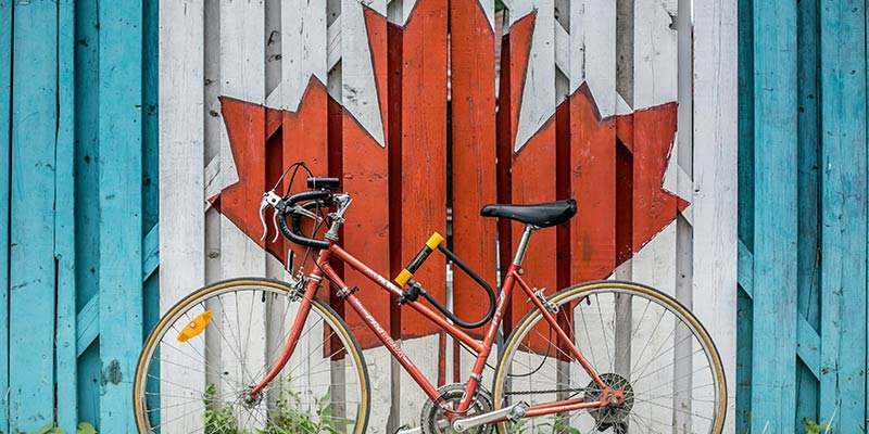 Road bike leaned against fence painted with maple leaf