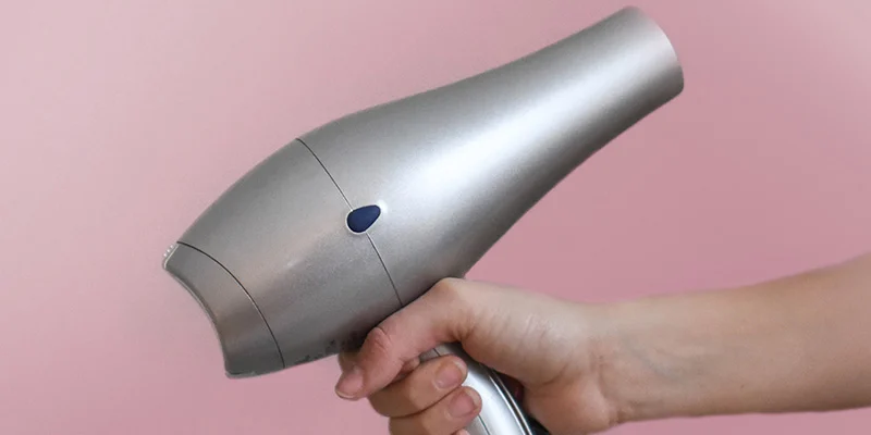 Hand holding a metallic hairdryer