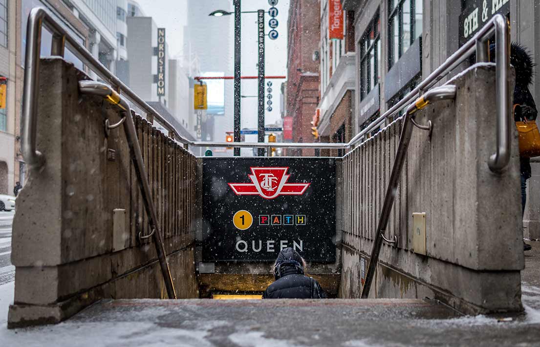 Person walking down steps into subway station in Toronto, Ontario