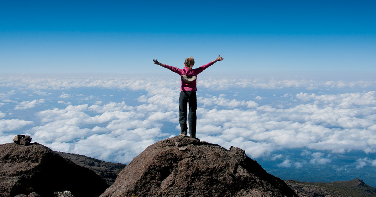 Woman standing at the summit of Kilimanjaro