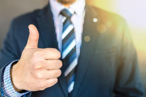 Man in suit and tie giving thumbs up