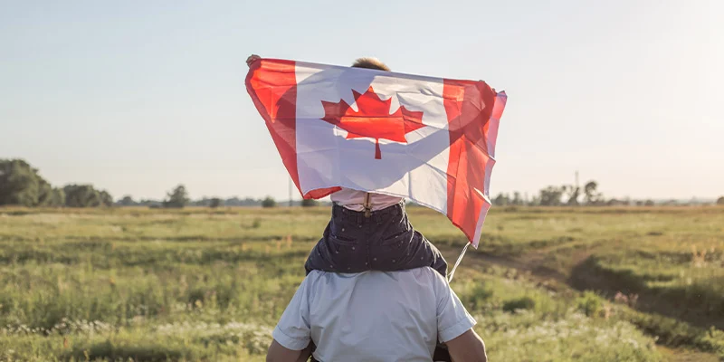 Older man and grandson holding Canadian Flag.
