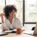 Smiling, happy, young woman working at home with laptop