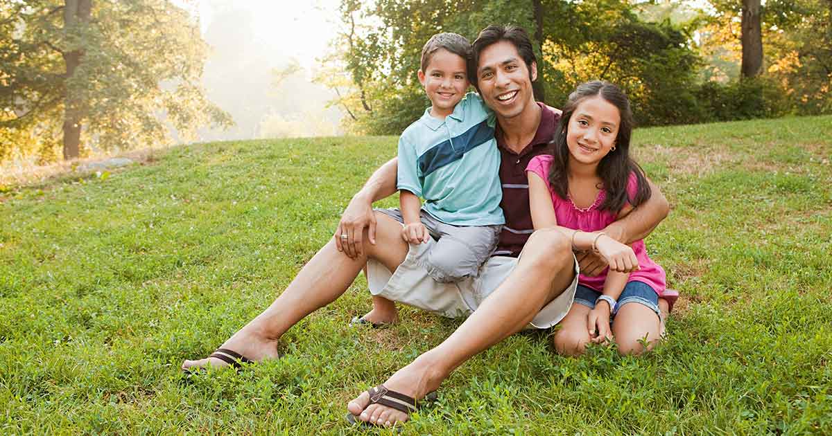 Filipino man with two children on a grassy lawn