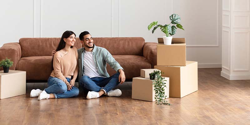 Family relaxing on floor in new home with cardboard boxes