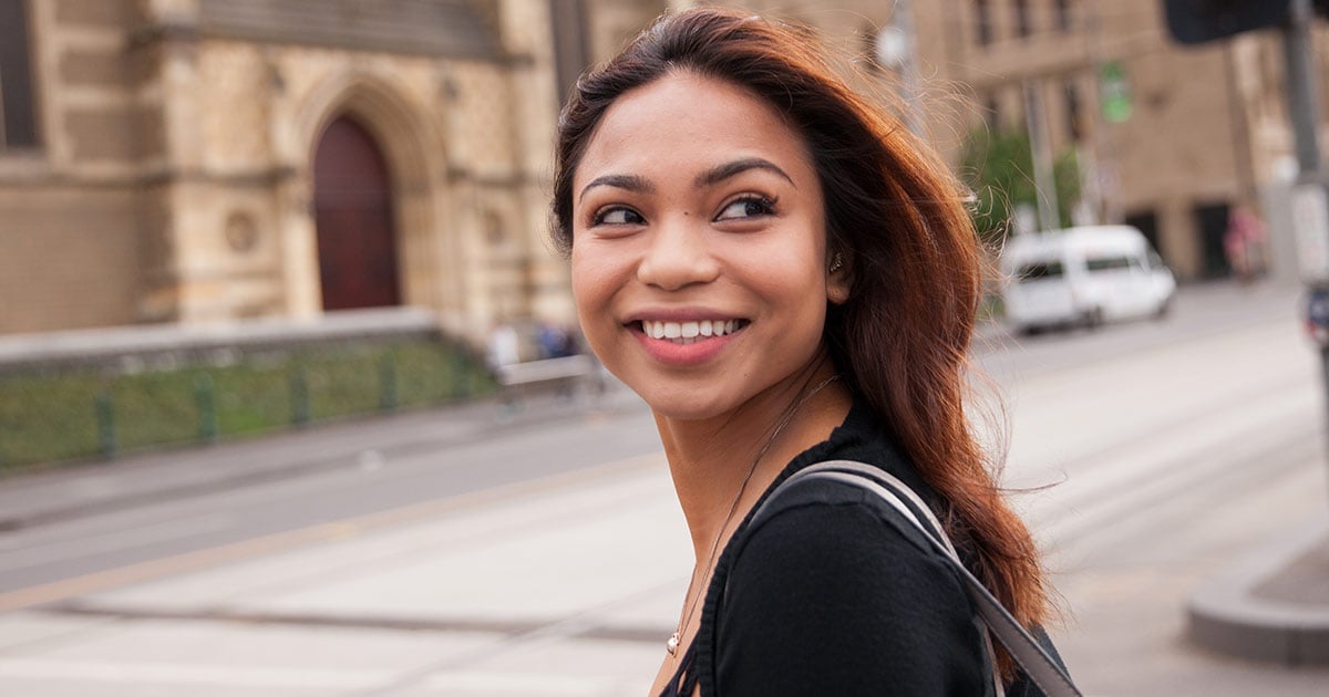 Filipino woman looking over shoulder smiling on the street