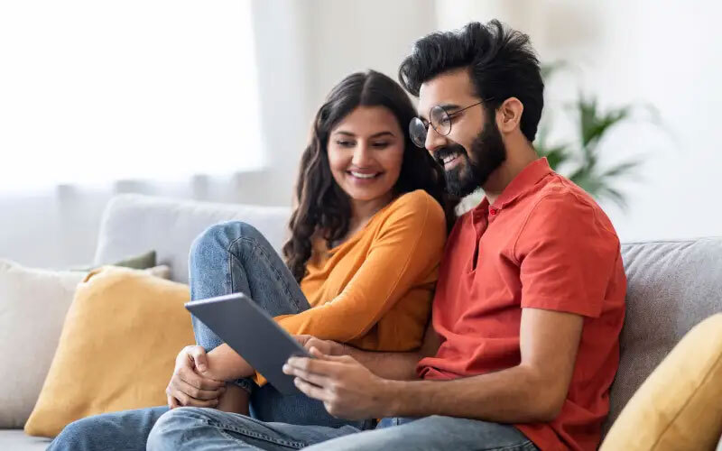 Man and woman smiling staring at a tablet.