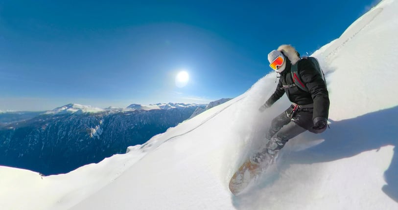 Female freerider shredding the un-groomed slopes in the beautiful Canadian backcountry. Female heliboarder enjoying her winter holidays in the pristine mountains of British Columbia.