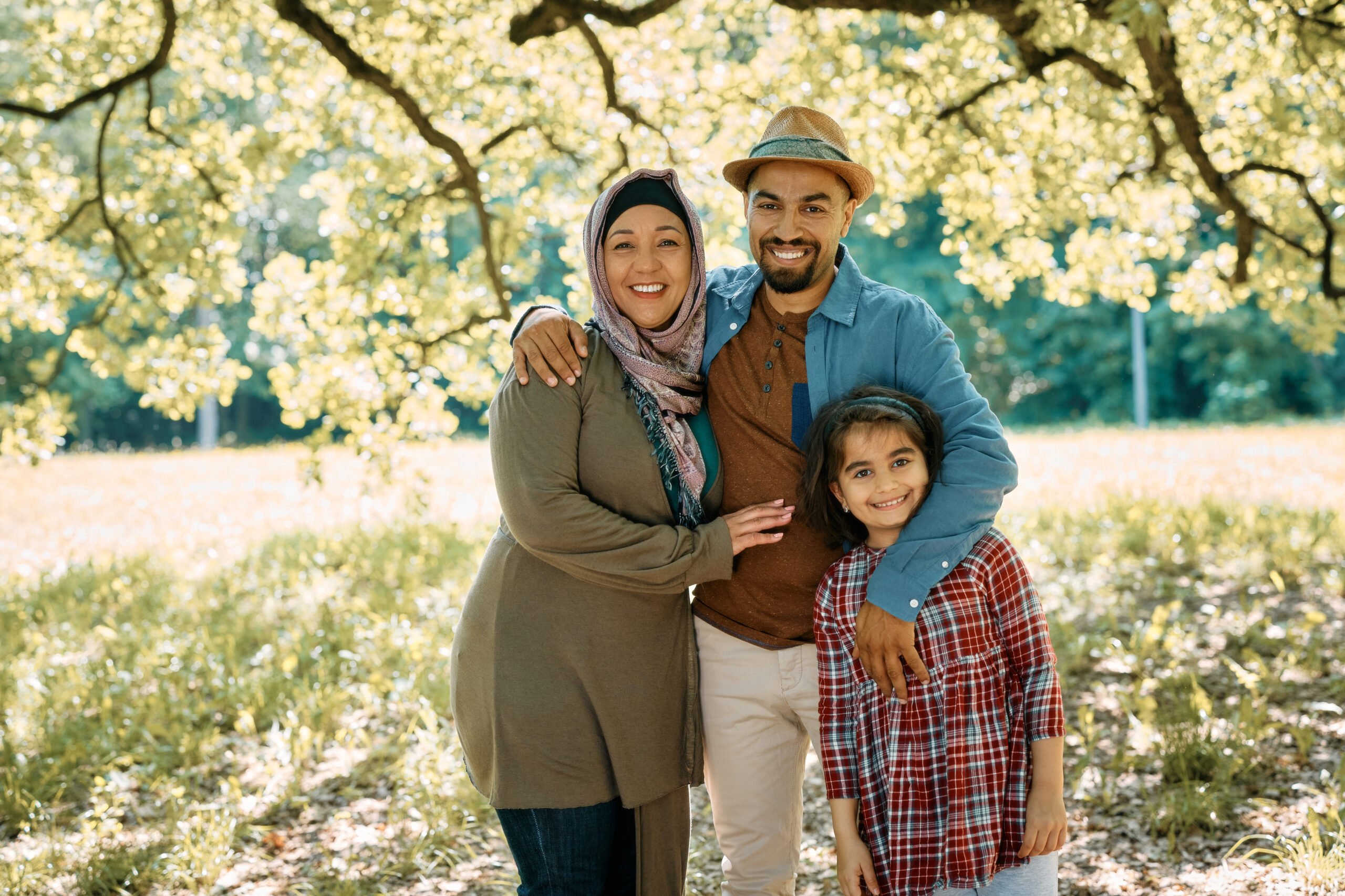 Portrait of happy Muslim parents and their daughter in the park looking at camera.