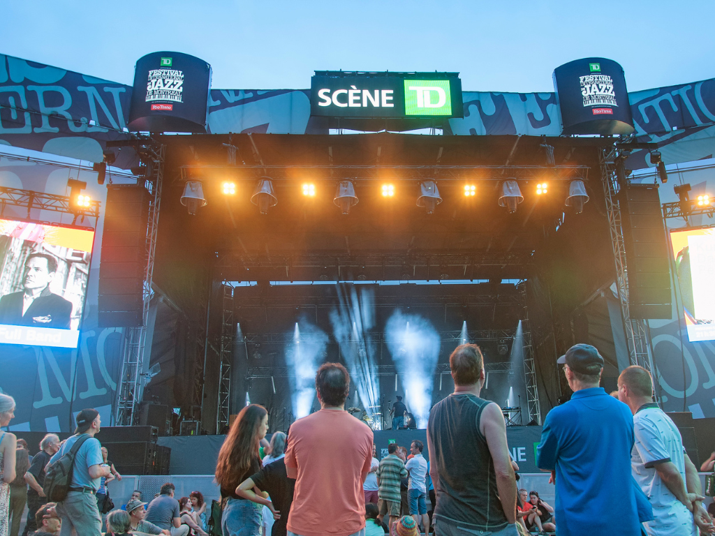 Audience members gather in front of a large outdoor stage at the Montreal International Jazz Festival in Quebec.