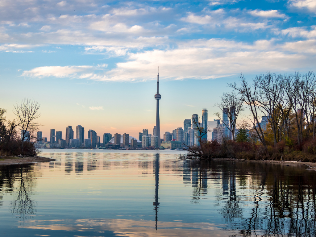 A serene view of the Toronto Islands in Ontario with the iconic Toronto skyline, including the CN Tower against a clear blue sky