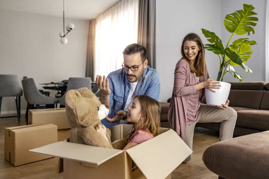 Family unpacking boxes in living room.