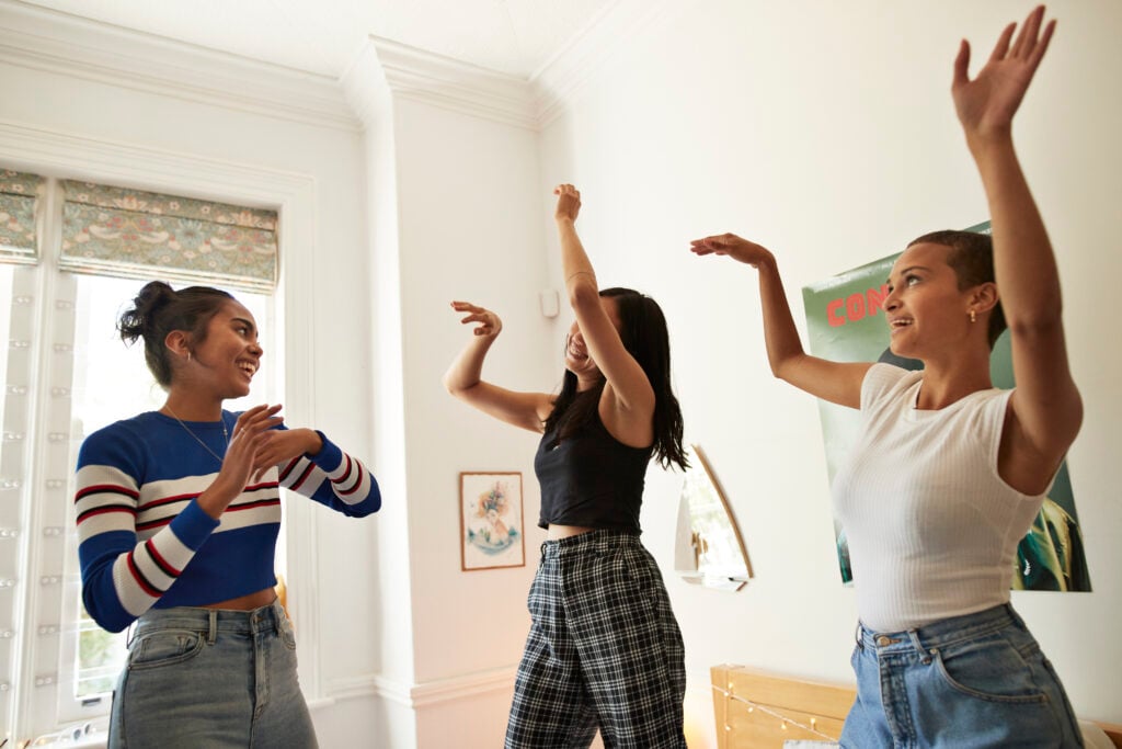 Happy young friends dancing enjoying in bedroom