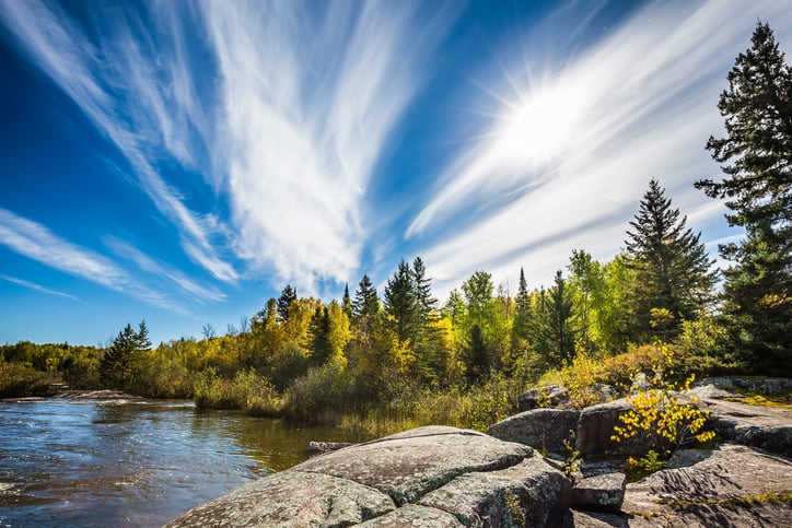 Incredible cirrus clouds and huge flat stones in Old Pinawa Dam Park. Indian summer in Manitoba, Canada. The concept of ecological and recreational tourism