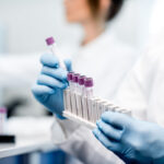 Laboratory assistant putting test tubes into the holder, Close-up view focused on the tubes