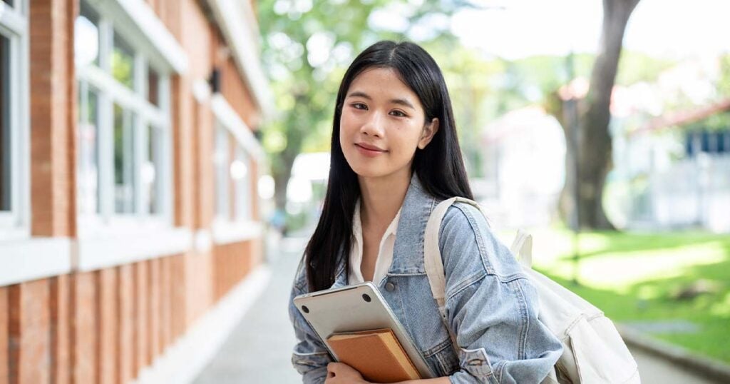 Smiling student holding books outdoors